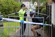 A police officer lifts a cordon to allow a person out from a crime scene in Hainault, east of London on April 30, 2024.