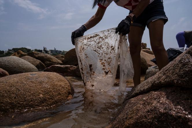 Un volontaire ramasse des déchets plastiques lors d’une opération de nettoyage des plages à Hongkong, le 14 avril 2024.