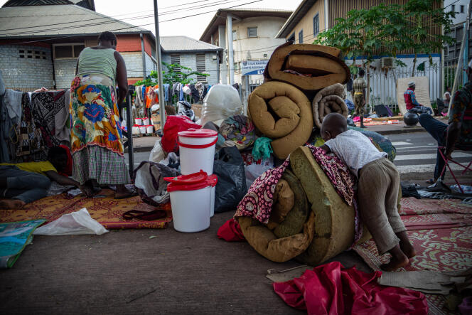 A Mamoudzou, dans le quartier du stade de Cavani, des réfugiés roulent nattes et matelas afin de ne pas gêner le passage sur les trottoirs, le 20 avril 2024 à Mayotte.