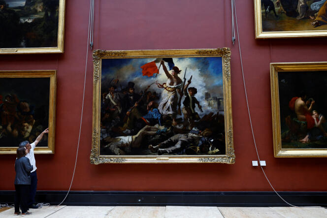 Empleados instalan el cuadro “La libertad guiando al pueblo”, de Eugène Delacroix, tras seis meses de restauración, en el Museo del Louvre de París, el 30 de abril de 2024.