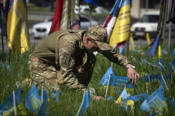 Un soldat ukrainien installe un drapeau national sur une pelouse de la place de l’Indépendance à Kiev, le 1ᵉʳ mai 2024.