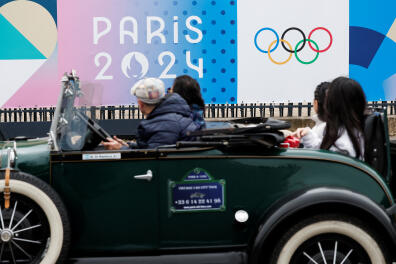Tourists drive past the logo of the Paris 2024 Olympic and Paralympic Games in front of the National Assembly in Paris, France, May 2, 2024. REUTERS/Benoit Tessier