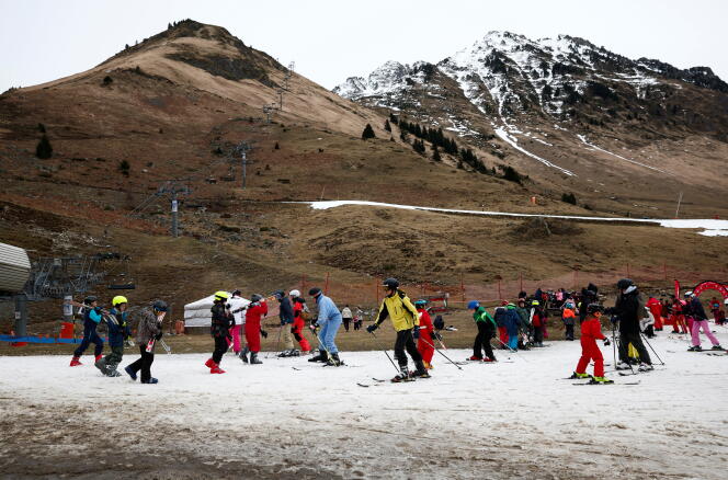 Skiers cross an artificial snow slope on a mild winter day in a ski resort (Hautes-Pyrénées) on February 21, 2024.