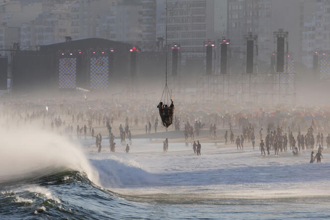 Lifeguards and a rescued person are transported in a helicopter's basket as people gather at Copacabana beach near the stage where Madonna will hold a concert, in Rio de Janeiro, on May 4, 2024.