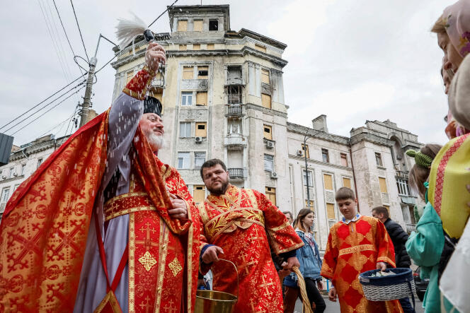 A priest sprays holy water on believers during an Easter service in front of a recently damaged residential building by a Russian missile strike, amid Russia's invasion of Ukraine, outside of the St. Nicholas Church, amid Russia's attack on Ukraine, in Kyiv, Ukraine, May 5, 2024. 