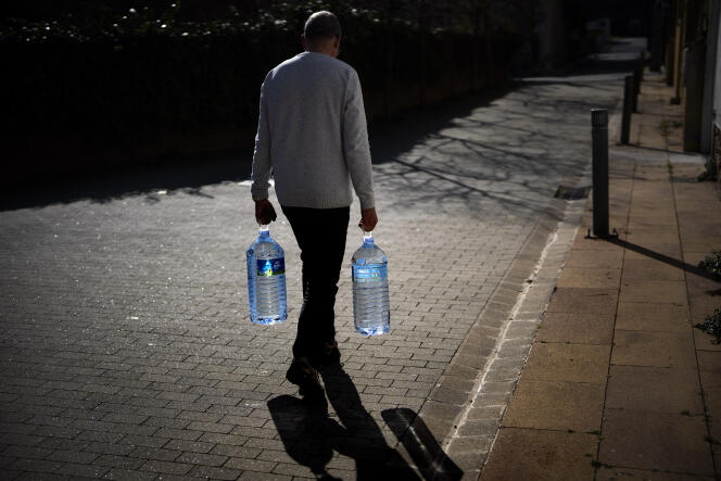 Un homme transporte deux bidons remplis d'eau jusqu'à une source naturelle à Gualba, dans la région de Barcelone (Espagne), le 31 janvier 2024. 