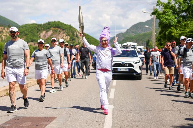 Cette photo prise et diffusée le 11 mai 2024 par le Comité d’organisation des Jeux olympiques et paralympiques de Paris 2024 (Cojop) montre la drag queen française Miss Martini tenant la flamme olympique dans le cadre du relais de la flamme, dans les rues de Digne-les-Bains.