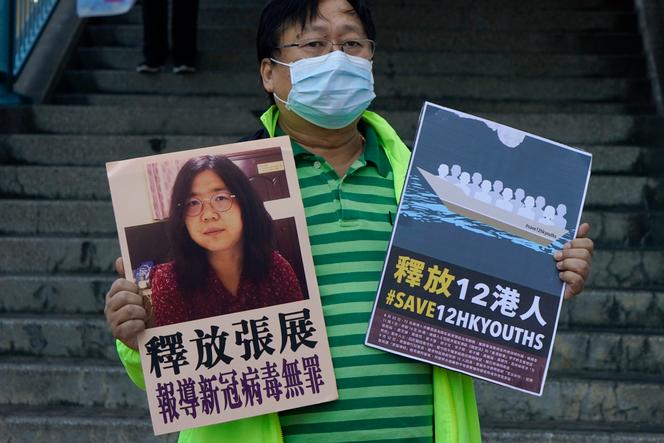 Un manifestant prodémocratie brandit une affiche montrant la photo de la blogueuse chinoise Zhang Zhan devant un bâtiment officiel chinois, à Hong Kong, le 28 décembre 2020.