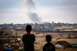 Des enfants observent la fumée au-dessus de Rafah (sud de la bande de Gaza), après des frappes israéliennes, le 13 mai 2024.