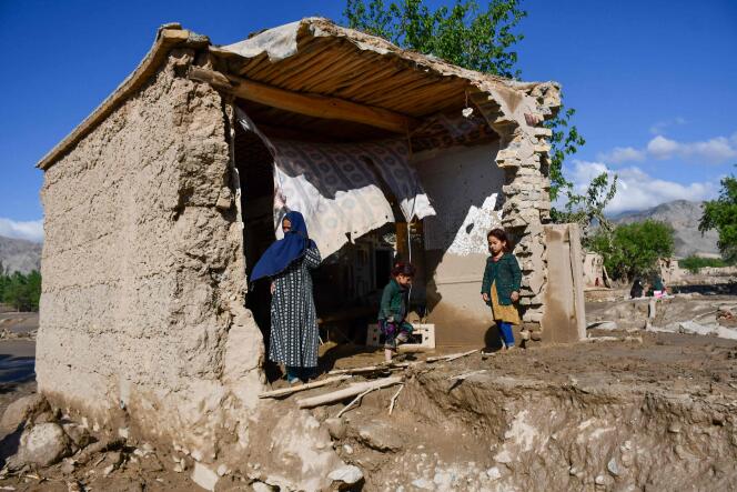 Des Afghans se tiennent devant leur maison endommagée par les inondations dans le district de Burka, dans la province de Baghlan, le 12 mai 2024. 