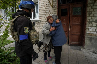Un policier patiente pendant que deux femmes se disent au revoir, lors d’une opération d’évacuation de la ville de Kharkiv, 13 mai 2024.