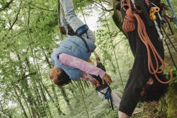 Une fillette suspendue à la branche d’un hêtre, dans la forêt proche de la commune de Champagneux (Savoie), le 16 avril 2024.