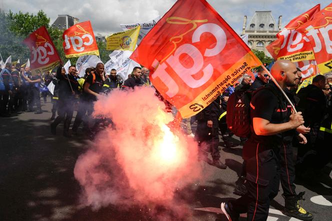 Des pompiers manifestent avec des drapeaux de la CGT, à Paris, le 16 mai 2024.