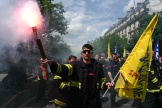 Un pompier brandit un drapeau et un fumigène lors de la manifestation des sapeurs-pompiers pour réclamer une prime JO, jeudi 16 mai 2024, à Paris.