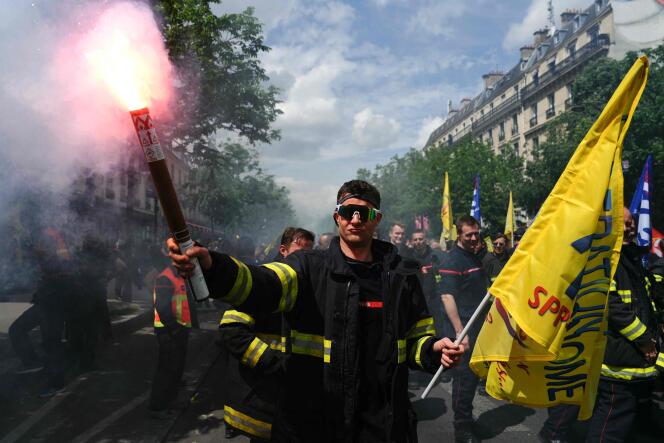 Un bombero blande una bandera y una bomba de humo durante la manifestación de los bomberos para exigir un bono olímpico, el jueves 16 de mayo de 2024, en París.