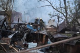 Des pompiers dégagent les débris de maisons dans la banlieue de Kharkiv, en Ukrainre, après l’attaque de drones russes, le 21 mai 2024.