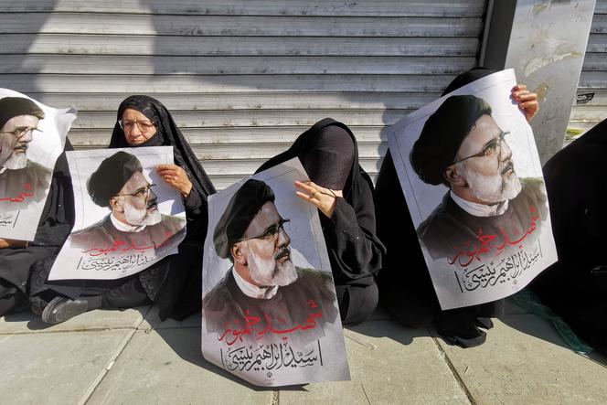 Le persone portano poster del presidente iraniano Ebrahim Raisi durante la cerimonia funebre per lui e i suoi compagni morti in un incidente in elicottero, a Teheran, il 22 maggio 2024. 