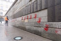 Un employé municipal nettoie le Mur des Justes couvert de graffitis de mains rouges devant le Mémorial de la Shoah, à Paris, le 14 mai 2024.
