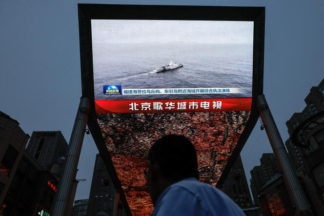 En Beijing, el 23 de mayo de 2024, un transeúnte mira las noticias que informan sobre los ejercicios militares llevados a cabo en la isla de Taiwán por el ejército chino.