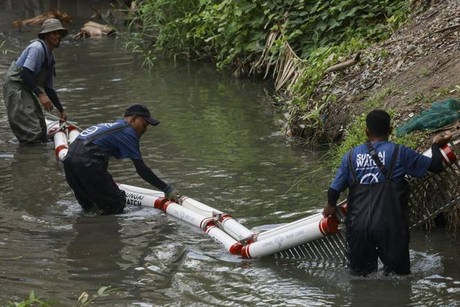 Miembros de la asociación Sungai Watch instalan una barrera en un río en el distrito de Kerobokan, en la isla indonesia de Bali, el 14 de diciembre de 2023.