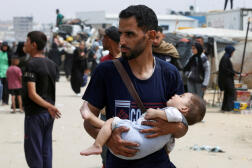 Un homme porte un enfant en fuyant Rafah, dans le sud de la bande de Gaza, le 28 mai 2024. 