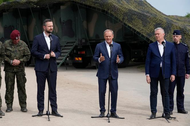 Polski premier Donald Tusk (w środku) jest otoczony przez ministra obrony Władysława Kosiniaka-Kamysza (po lewej) i jego odpowiednika w sprawach wewnętrznych Tomasza Siemoniaka (po prawej) w Dubiczach Cerkiewnych, wschodnia Polska, 29 maja 2024 r.