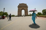 A woman holding an umbrella walks near the India Gate during severe heatwave on a hot summer day in New Delhi on May 29, 2024. 