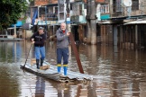 Deux hommes pagayent dans une rue inondée du quartier de Vila-Farrapos, à Porto Alegre (Brésil), le 29 mai 2024.