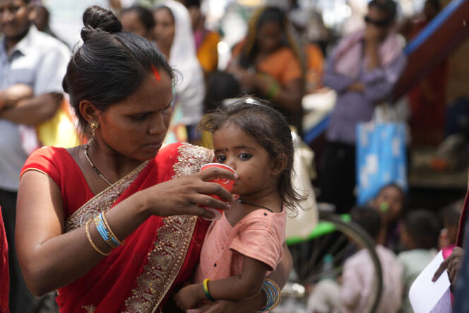 Una mujer hace beber a su hija durante una distribución de agua por parte de una ONG, en medio de una ola de calor en Nueva Delhi, el jueves 30 de mayo de 2024.