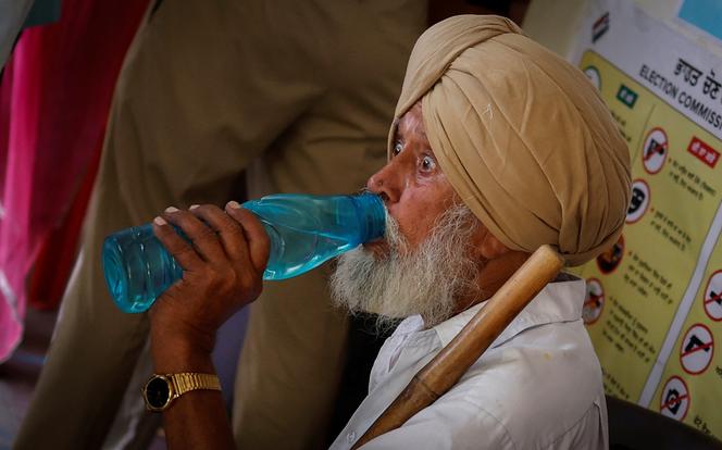 Un homme boit de l'eau en attendant de voter devant un bureau de vote lors de la septième et dernière phase des élections générales dans le district de Faridkot, dans l'État du Pendjab, en Inde, le 1er juin 2024.