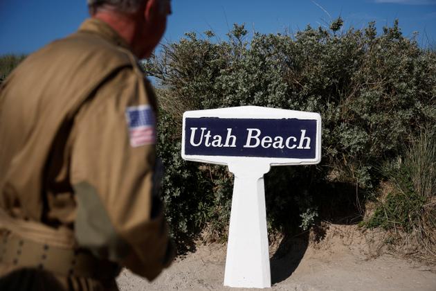A World War II reenactor walks near a sign on Utah Beach, ahead of the 80th anniversary of the 1944 D-Day landings in Sainte-Marie-du-Mont, Normandy region, France, June 2, 2024. 