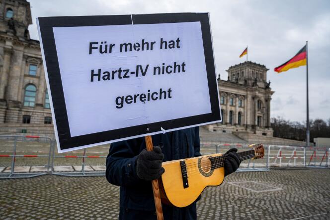 Un militant pose avec une pancarte où il écrit « Voici tout ce que vous rapporte Hartz IV », devant le Bundestag à Berlin, en 2021.