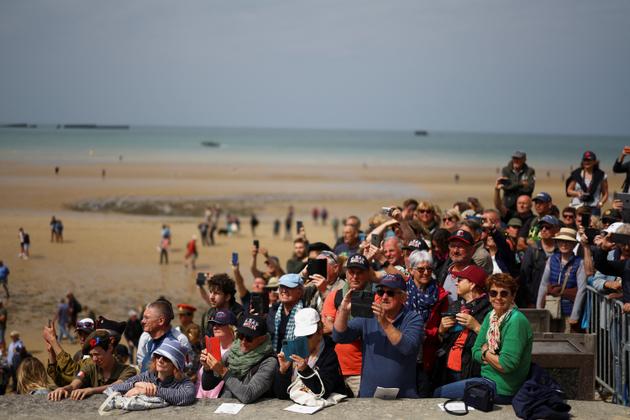 People watch and record a parade marking the 80th anniversary of D-Day at Arromanches, Normandy region, France, June 6, 2024. REUTERS/Hannah McKay