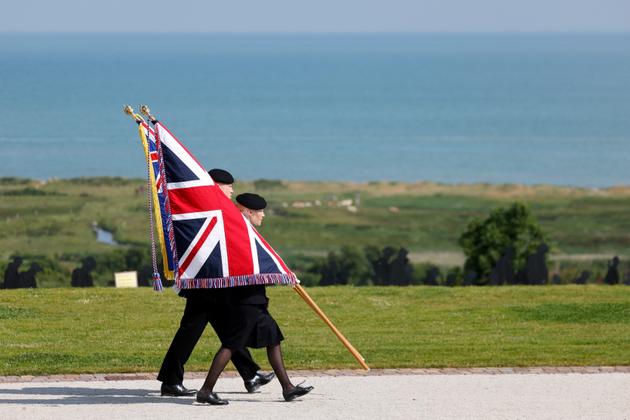 A person carries the Union Jack flag during the commemorative ceremony marking the 80th anniversary of D-Day at the World War II British Normandy Memorial near the village of Ver-sur-Mer which overlooks Gold Beach in northwestern France, on June 6, 2024. 
