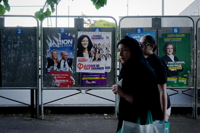 Deux femmes passent devant une affiche électorale du parti « Reconquête » dans le centre d’Evry, dans l’Essonne, le 9 juin 2024.