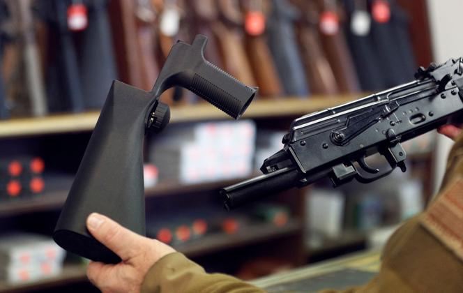 Een schokkolf, links, die op een semi-automatisch geweer kan worden gemonteerd om de vuursnelheid te verhogen, naast een AK-47 semi-automatisch geweer, rechts, bij een wapenwinkel, Salt Lake City, Utah (VS), 5 oktober .  2017.