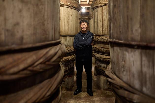 Grandson of the founder of Yugeta, Yohichi Yugeta stands between wooden barrels where soybeans naturally ferment. Here on May 13, 2024.