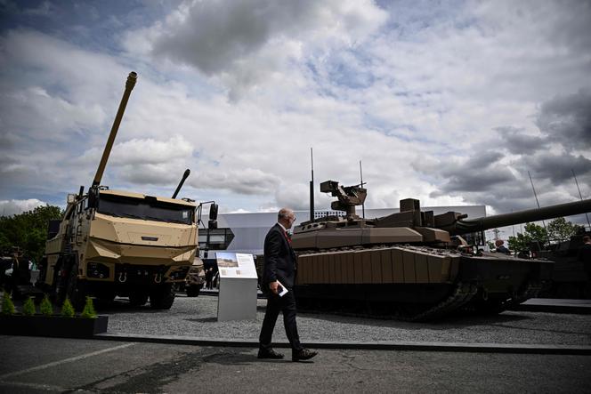Um visitante passa em frente a um caminhão militar equipado com um canhão Cesar e um tanque Leclerc da Nexter Systems durante a exposição internacional Eurosatory, dedicada à defesa e segurança terrestre e aérea, em Villepinte, em Seine-Saint-Denis, em 17 de junho de 2024.
