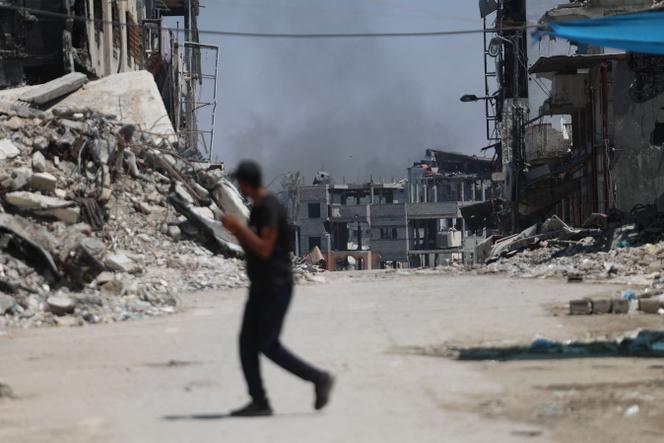 Palestyńczyk przechodzi przez ulicę, w tle unosi się dym z obszaru będącego celem izraelskich bombardowań, w rejonie Chadjaya w mieście Gaza, 28 czerwca 2024 r.