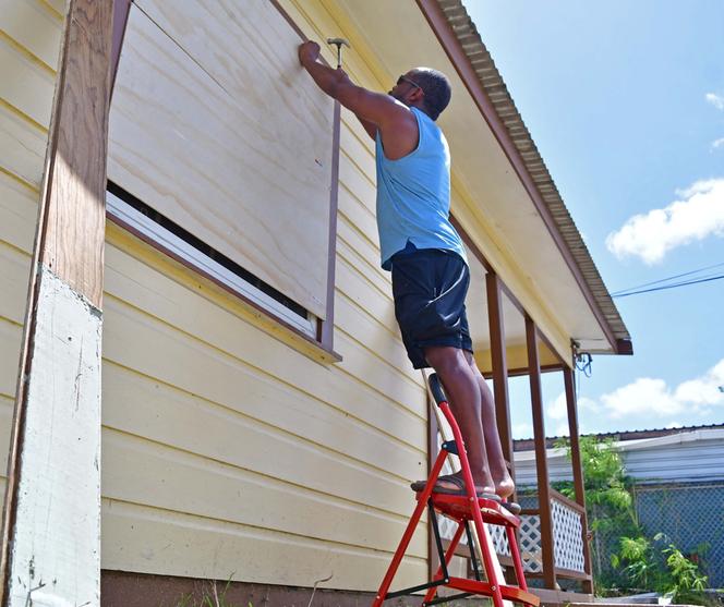 A Bridgetown, la capitale de la Barbade, un homme tente de protéger sa maison en clouant des planches à ses fenêtres avant l’arrivée de l’ouragan Béryl, le 30 juin 2024.