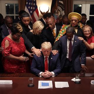 WASHINGTON, DC - FEBRUARY 27: African American supporters lay their hands on U.S. President Donald Trump as they pray for him at the conclusion of a news conference and meeting in the Cabinet Room at the White House February 27, 2020 in Washington, DC. The president talked about the economic advances African Americans have made under his administration, about the government's response to the global coronavirus threat and how dishonest he thinks the news media can be to him. He did not answer reporters' questions about the S&P 500 taking its worst loss in almost nine years.   Chip Somodevilla/Getty Images/AFP (Photo by CHIP SOMODEVILLA / GETTY IMAGES NORTH AMERICA / Getty Images via AFP)
