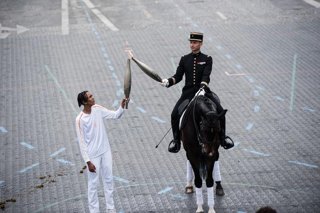 Colonel Thibault Vallette, chief equerry of the Cadre Noir de Saumur, passes the Olympic flame on Avenue Foch, Paris, on July 14, 2024.