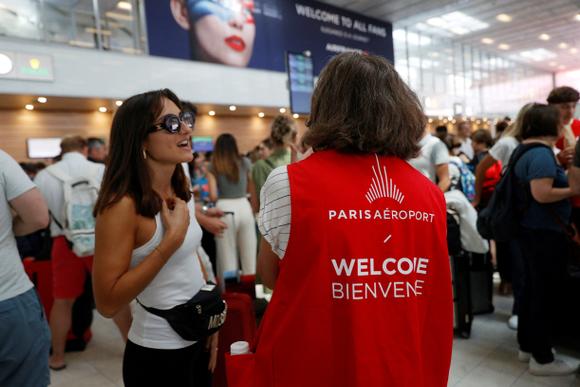 Un dipendente del Gruppo ADP fornisce informazioni ai passeggeri al Terminal 3 dell'aeroporto di Orly, venerdì 19 luglio.