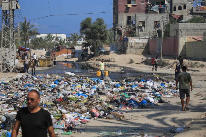 Des Palestiniens passent devant des eaux usées et une décharge dans une rue de Deir Al-Balah, dans le centre de la bande de Gaza, le 23 juillet 2024, alors que l’Organisation mondiale de la santé s’est inquiétée des risques d’épidémies.