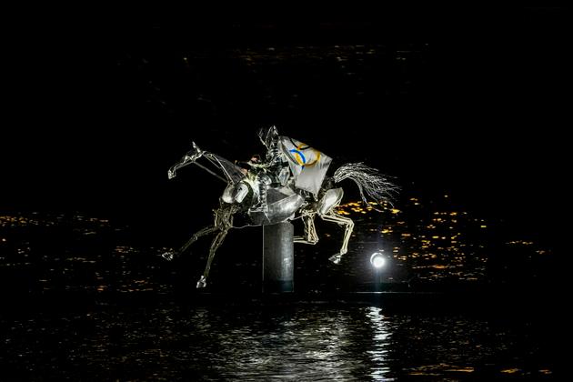 In Parijs, op 26 juli 2024, draagt ​​een mechanisch paard een ruiter die de Olympische vlag draagt, terwijl de nacht valt op de rivier de Seine, het toneel van de openingsceremonie van de Olympische Spelen.