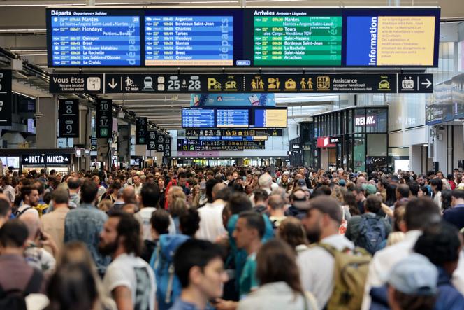 Vendredi 26 juillet, des passagers rassemblés autour des panneaux de départ et d’arrivée à la gare Montparnasse à Paris, alors que le réseau ferroviaire à grande vitesse français a été touché par des actes de malveillance.