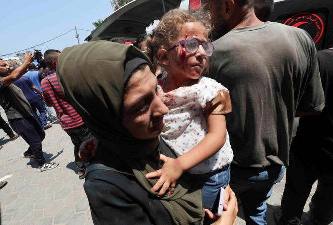 Eine Palästinenserin trägt nach einem israelischen Angriff auf eine Schule in Deir-al-Bala am 27. Juli 2024 ein verletztes Kind in ein Krankenhaus.