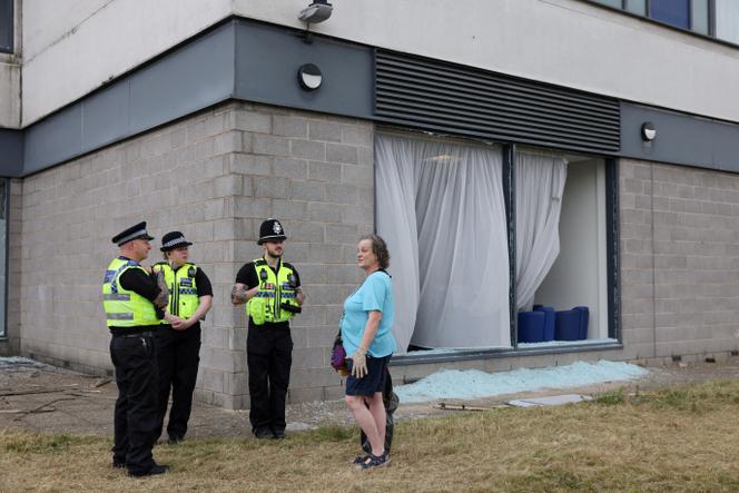 Des policiers discutent avec une riveraine, devant l’hôtel Holiday Inn de Rotherham (Royaume-Uni), vandalisé le 5 août 2024 par des manifestants d’extrême droite. 