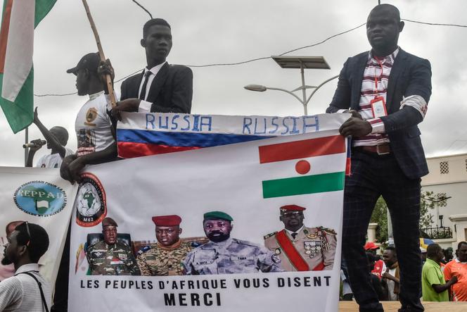 Des manifestants brandissent un drapeau russe avec des photos du général Abdourahamane Tiani, nouvel homme fort du Niger, du chef de la junte du Burkina Faso, le capitaine Ibrahim Traoré, du chef de la junte du Mali, Assimi Goïta, et du chef de la junte de Guinée, le colonel Mamadi Doumbouya, lors d’une manifestation le jour de l’indépendance, à Niamey, le 3 août 2023.