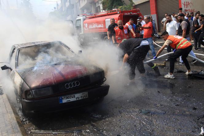 Des pompiers éteignent le feu dans une voiture après une attaque israélienne dans la ville libanaise de Saïda, le 21 août 2024.